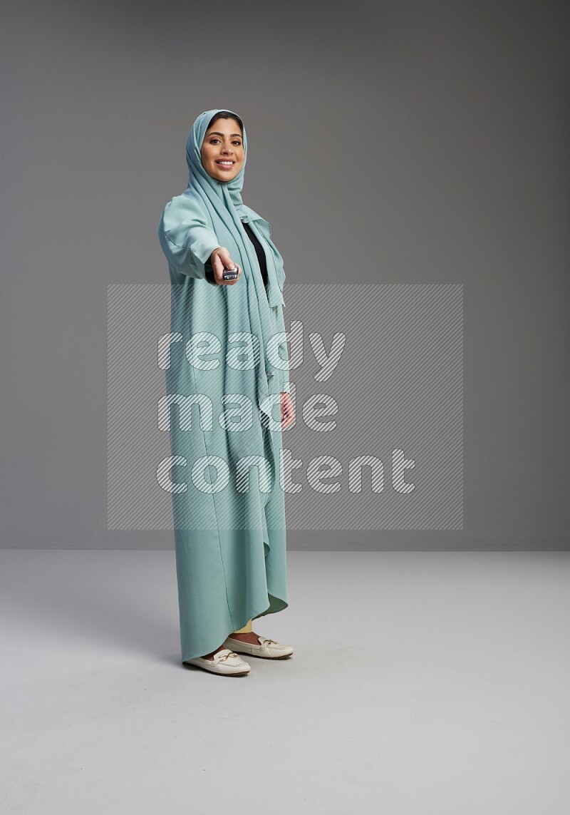 Saudi Woman wearing Abaya standing holding car key on Gray background