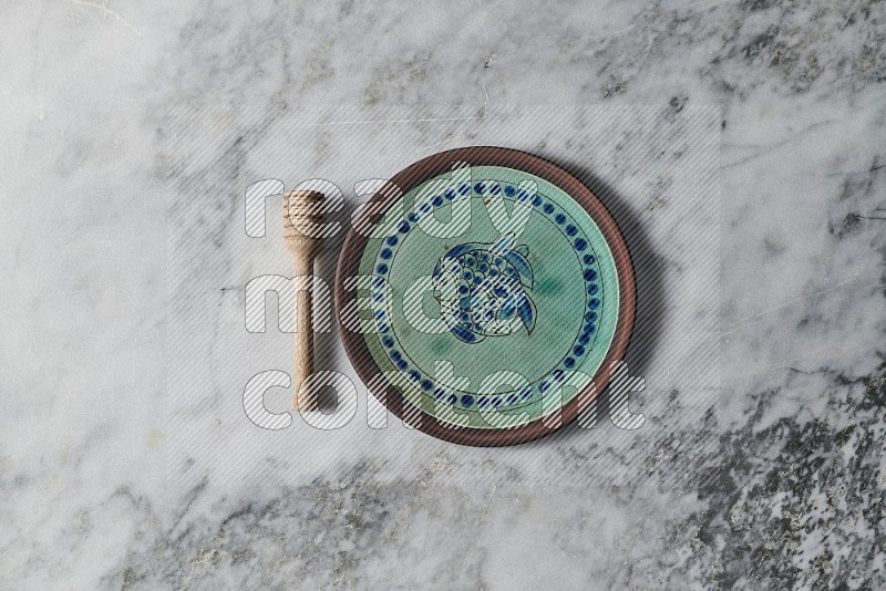 Decorative Pottery Plate with wooden honey handle on the side on grey marble flooring, Top view