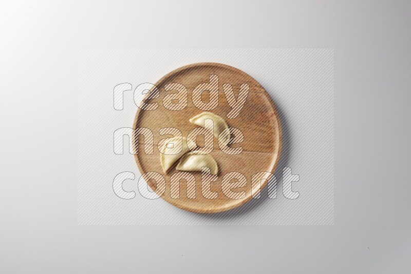 Three Sambosas on a wooden round plate on a white background