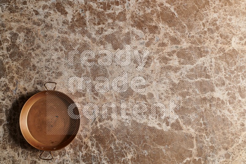 Top View Shot Of A Small Copper pan On beige Marble Flooring