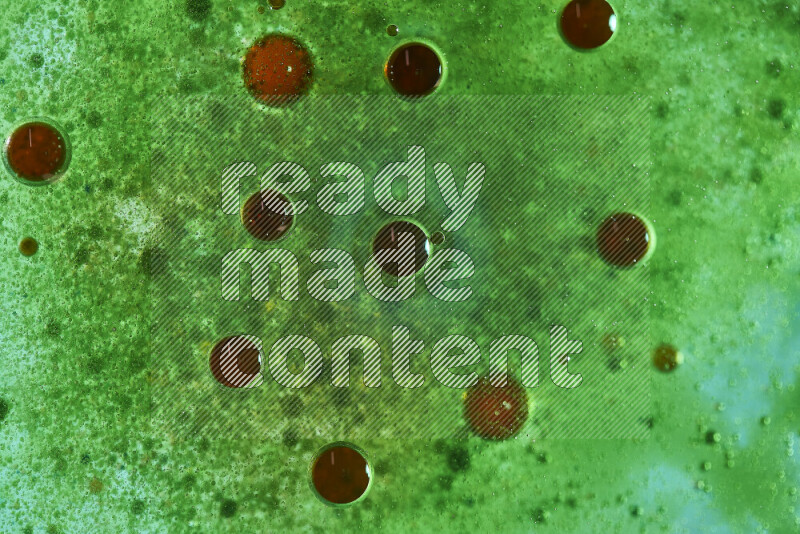 Close-ups of abstract red and green watercolor drops on oil Surface on green background