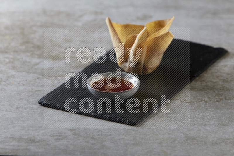 wonton cups with soy sauce ramkin on rectangle slate on grey textured counter top