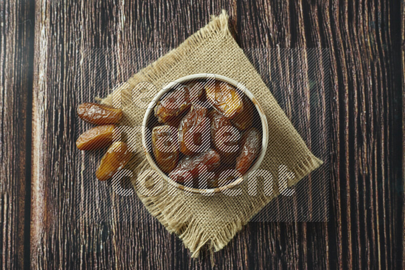 Dates in different bowls (wooden, pottery and glass) on wooden background