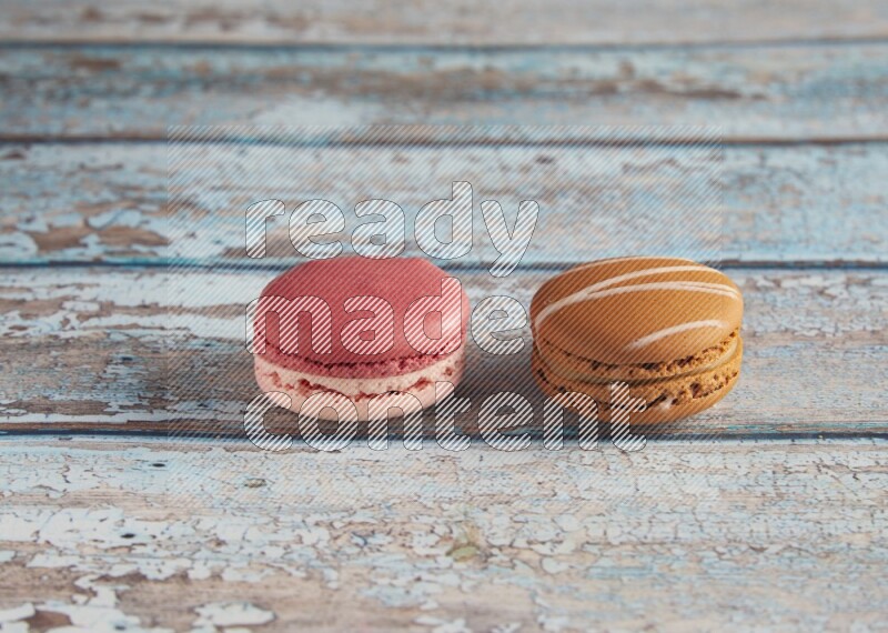 45º Shot of of two assorted Brown Irish Cream, and Pink Litchi Raspberry macarons on light blue background
