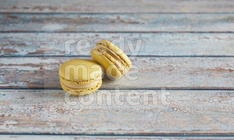 45º Shot of two Yellow Lime macarons on light blue wooden background