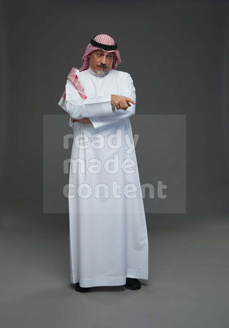 Saudi man with shomag Standing Interacting with the camera on gray background