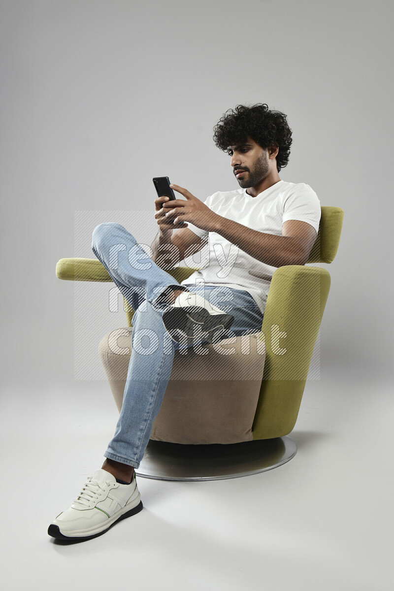 A man wearing casual sitting on a chair talking on the phone on white background