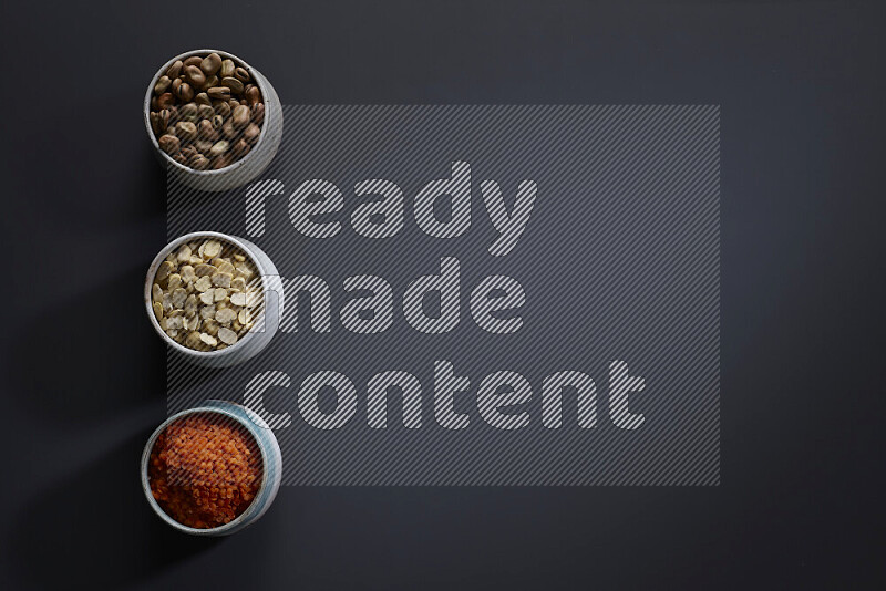 Legumes in pottery bowls on grey background
