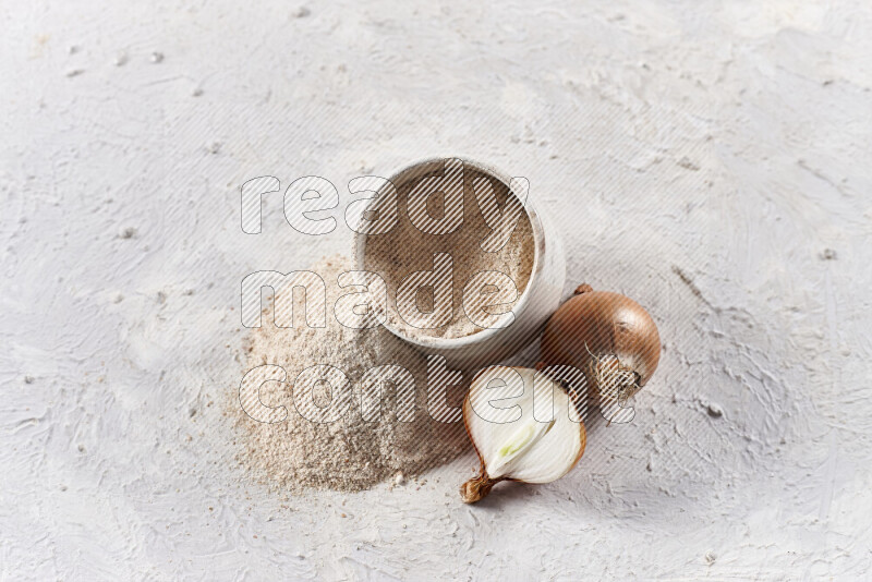 A beige pottery bowl full of onion powder with fallen powder from it on white background