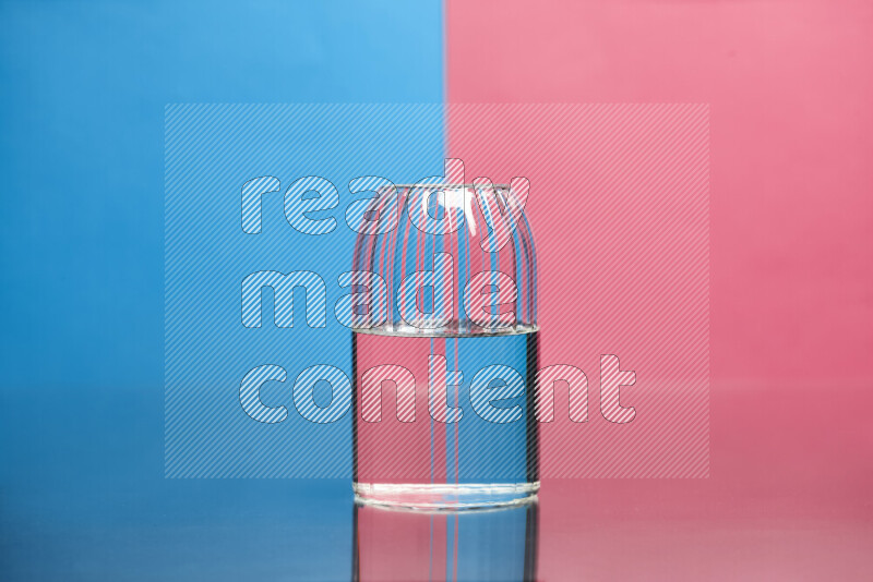 The image features a clear glassware filled with water, set against blue and pink background