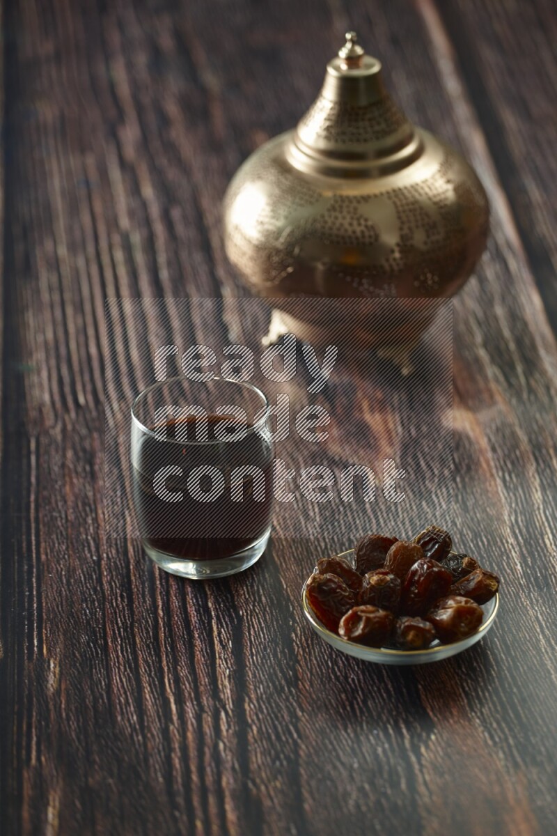 A golden lantern with different drinks, dates, nuts, prayer beads and quran on brown wooden background