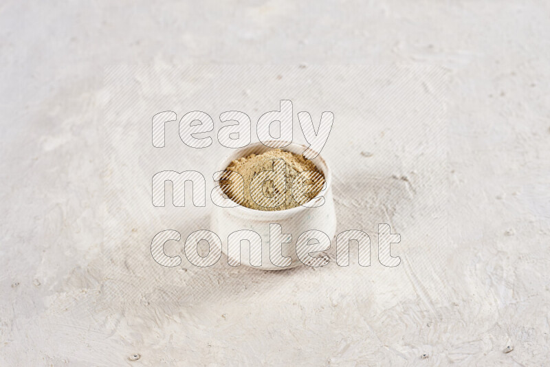 A beige pottery bowl full of ground ginger powder on white background