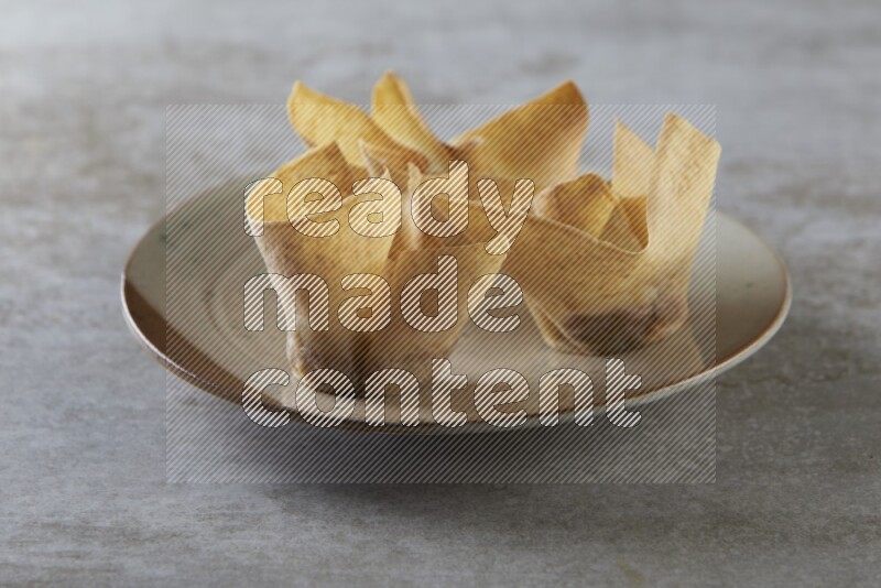 wonton cups with soy sauce ramkin on multi colored pottery on grey textured counter top