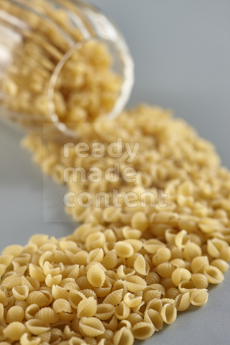 Flipped jar full of raw pasta on light blue background