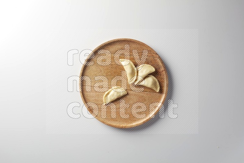 Four Sambosas on a wooden round plate on a white background
