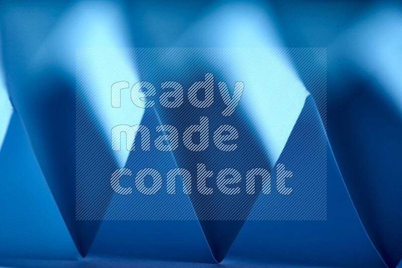 صورة مجردة مقربة تظهر طيات ورقية هندسية حادة بتدرجات اللون الأزرق