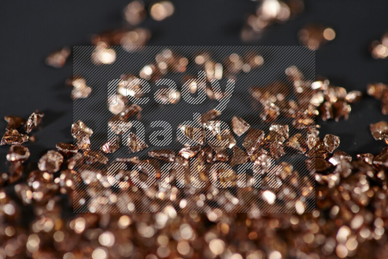 Bronze shimmering fragments of glass scattered on a black background
