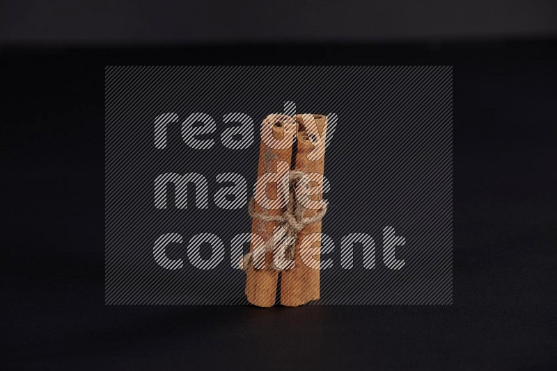 4 Cinnamon sticks stacked and bounded on black flooring