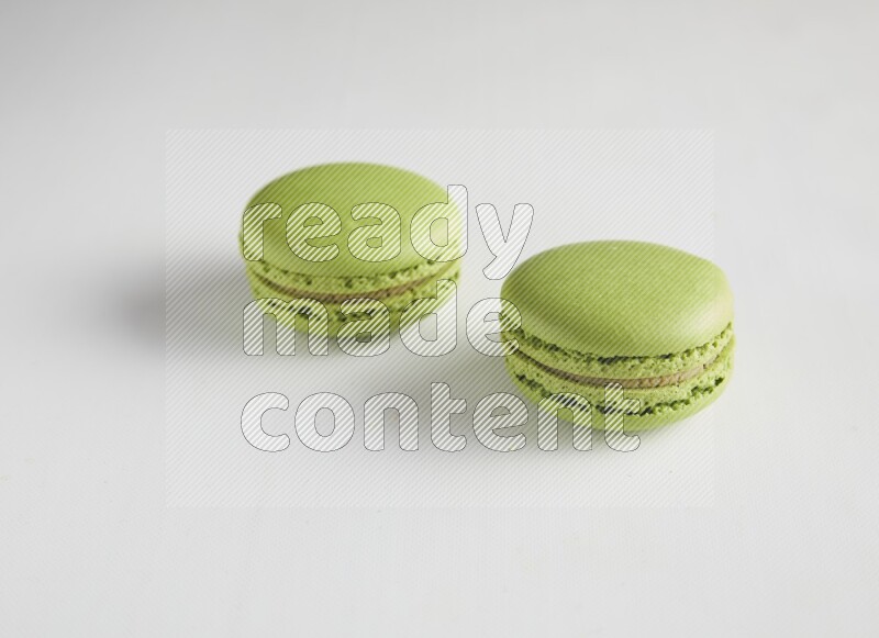 45º Shot of two Green Pistachio macarons on white background