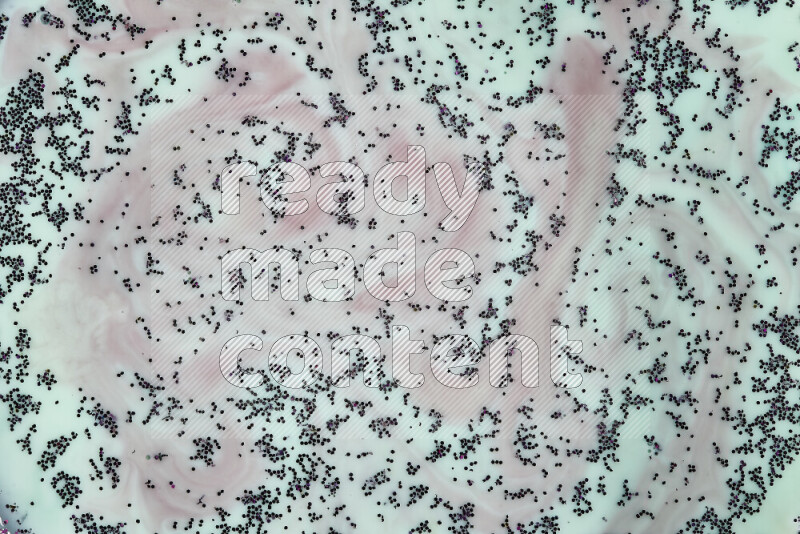 لقطة مقرّبة لدوامات من اللون الأحمر مع بريق أرجواني متلألئ منتشر على خلفية من اللون الأخضر