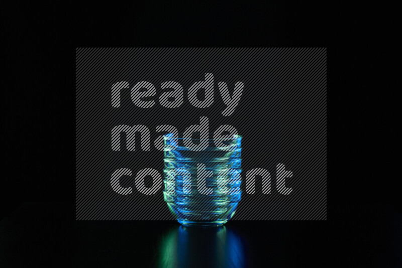 Glassware with rim light in blue and green against black background