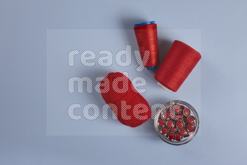 مجموعة من أدوات الخياطة والتفصيل حمراء اللون على خلفية زرقاء