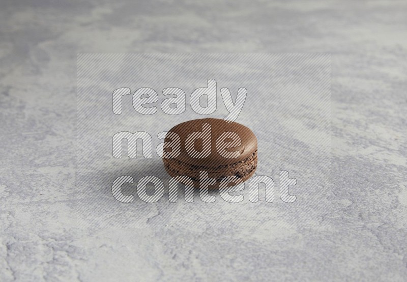 45º Shot of Brown Dark Chocolate macaron on white  marble background
