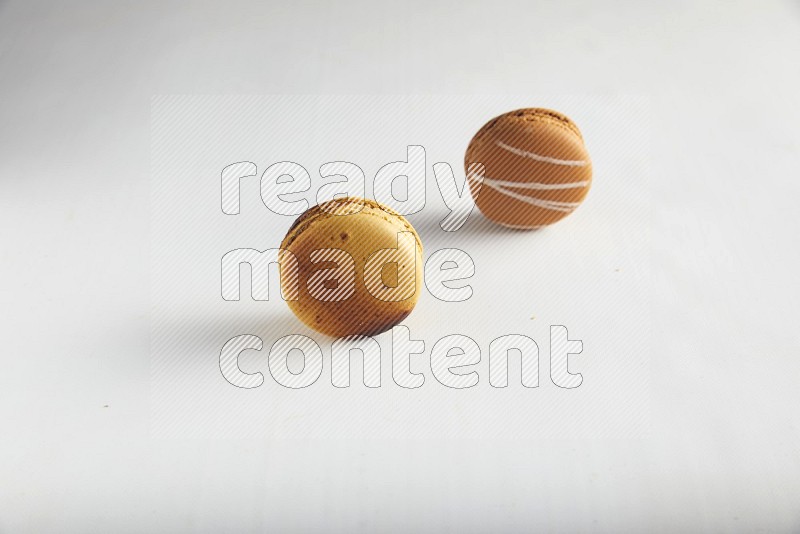 45º Shot of of two assorted Brown Irish Cream, and Yellow Crème Brulée macarons on white background