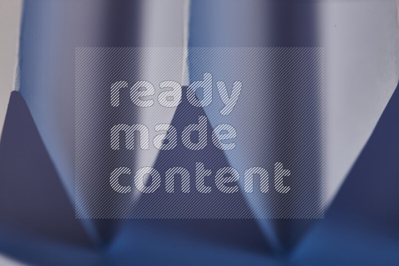 A close-up abstract image showing sharp geometric paper folds in blue gradients