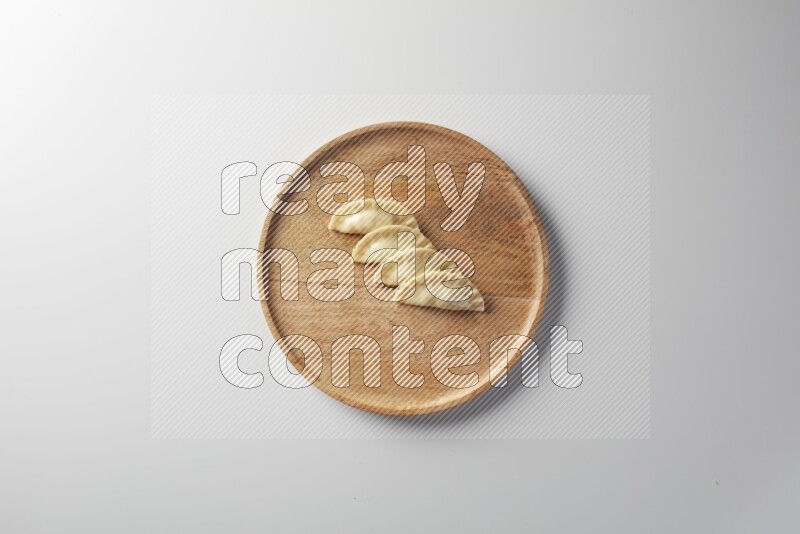 Four Sambosas on a wooden round plate on a white background
