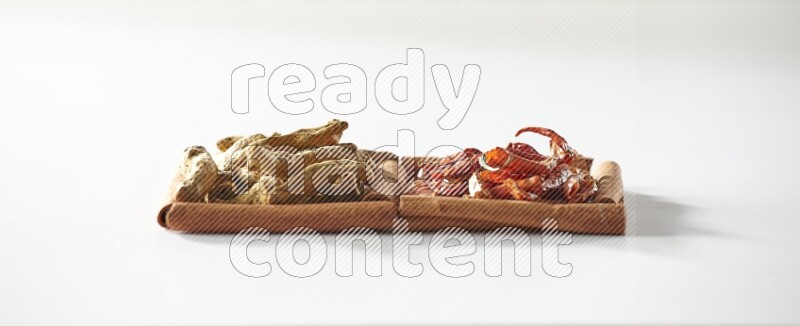 2 squares of cinnamon sticks full of dried red chilis and turmeric fingers on white flooring