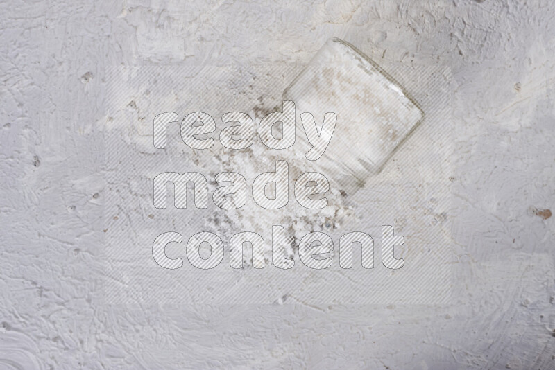 A glass jar full of coarse sea salt crystals on white background