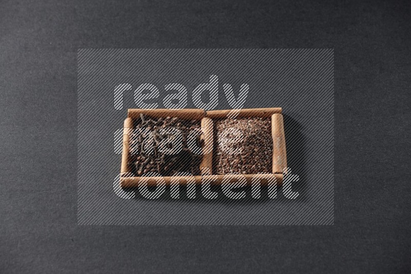 مربعان من أعواد القرفة ممتلئان ببذور الكتان والقرنفل علي خلفية سوداء