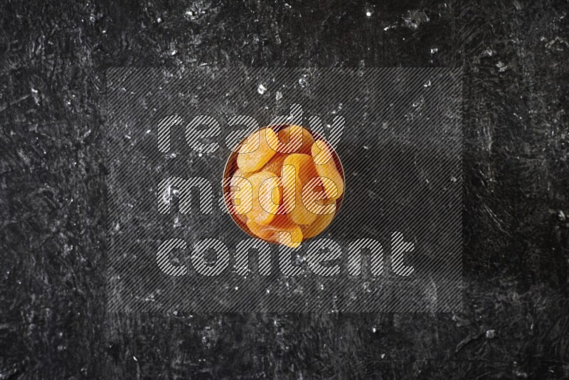 Dried fruits in a metal bowl in a dark setup