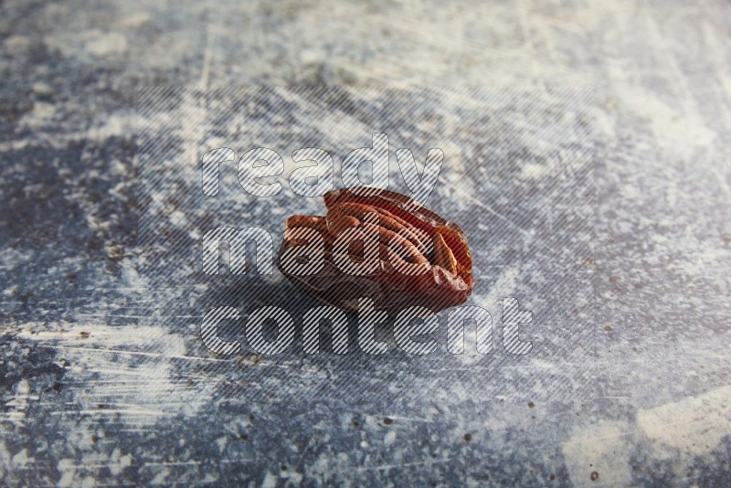 pecan stuffed madjoul date on a rustic blue background