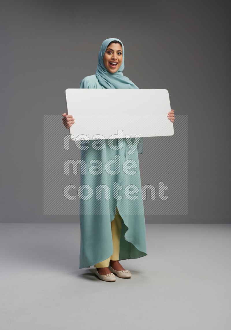 Saudi Woman wearing Abaya standing holding board on Gray background