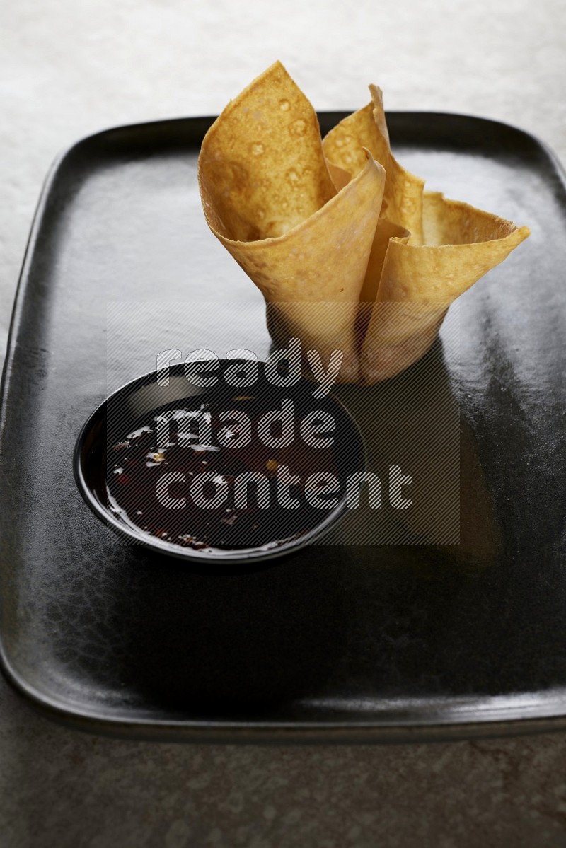 wonton cups with soy sauce ramkin on rectangle dark grey ceramic plate on grey textured counter top