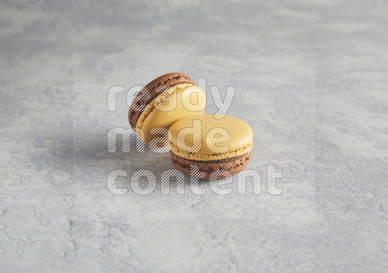 45º Shot of two Yellow and Brown Chai Latte macarons r on white  marble background