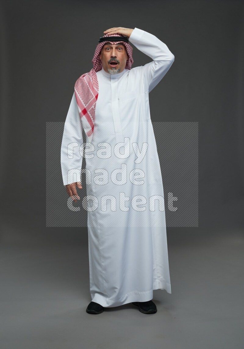 Saudi man with shomag Standing Interacting with the camera on gray background