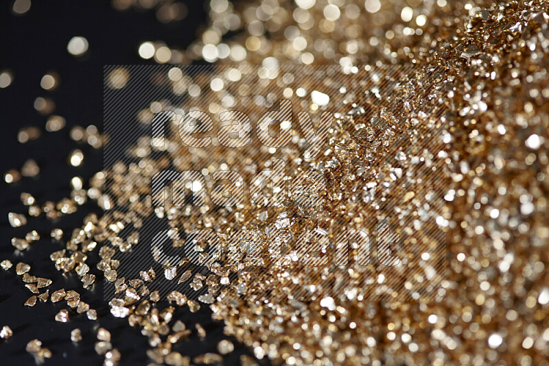 Gold shimmering fragments of glass scattered on a black background