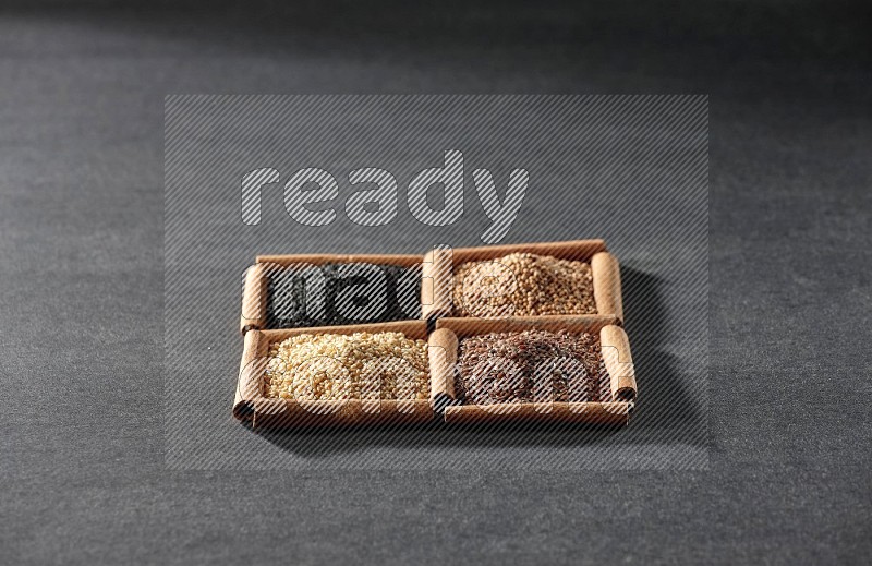 4 squares of cinnamon sticks full of black seeds, sesame, flaxseeds and mustard seeds on black flooring