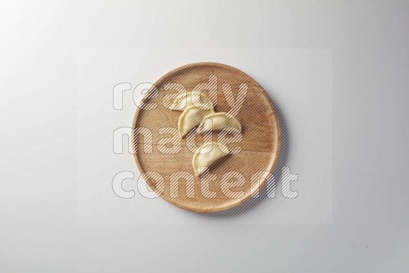 Four Sambosas on a wooden round plate on a white background