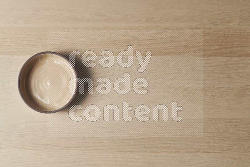 A beige pottery oven bowl on light wooden background