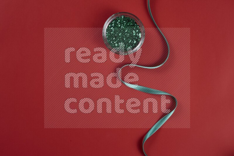 A green and red collection of sewing and tailoring tools arranged on a red background