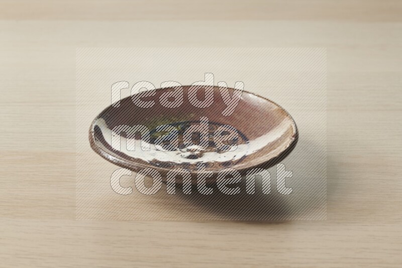 A decorative pottery plate on light wooden background