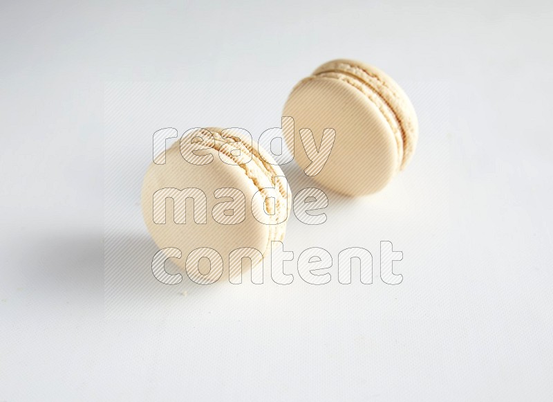 45º Shot of two White Caramel fleur de sel macarons on white background