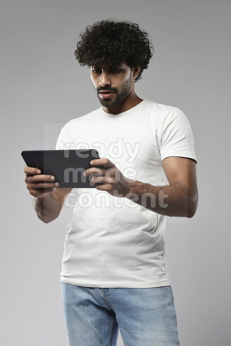 A man wearing casual standing and gaming on a tablet on white background