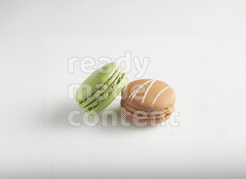 45º Shot of of two assorted Brown Irish Cream, and Green Pistachio macarons on white background