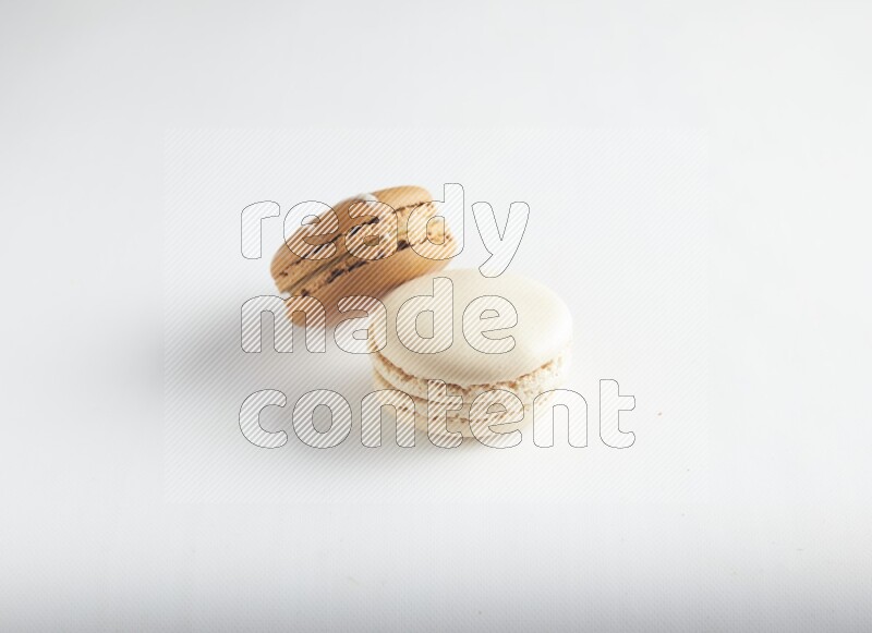 45º Shot of of two assorted Brown Irish Cream, and White Caramel fleur de sel macarons on white background