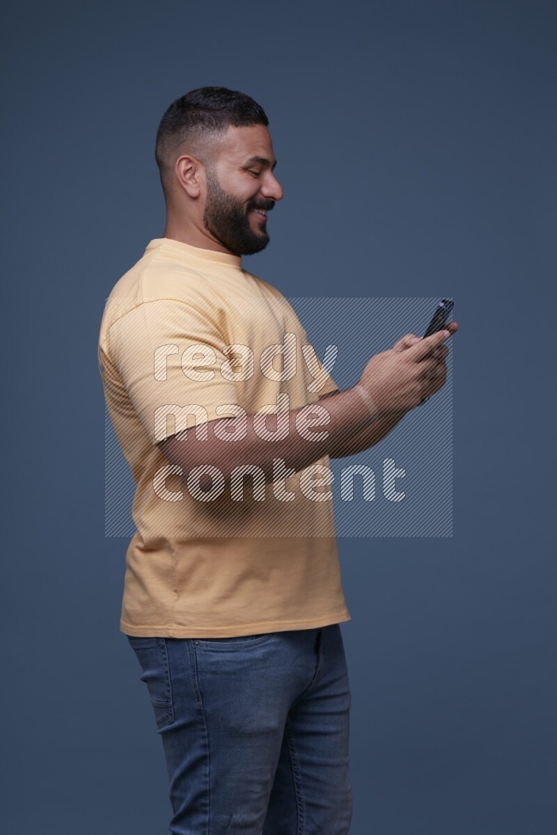 A man Texting on his phone in Blue Background wearing Orange T-shirt